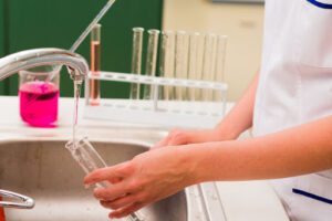 A lab assistant cleans a beaker.