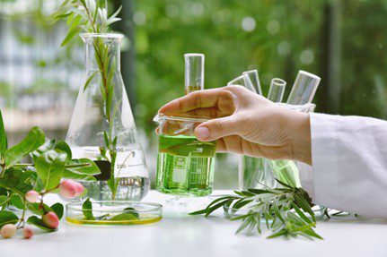 A close-up of a hand picking up a glass beaker.